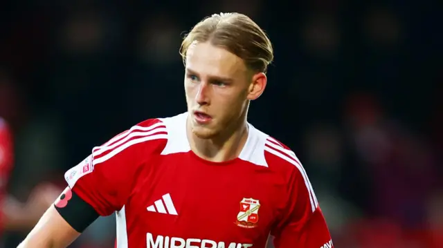 Finley Munroe, slightly leaning towards his left, has the ball at his feet for Swindon