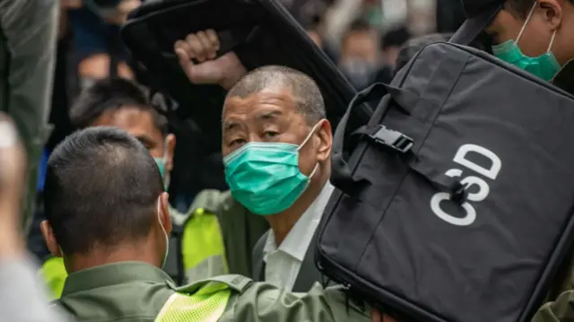 Jimmy Lai wearing a green mask looking to the side