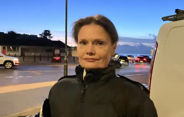 Nikki looking at the camera in a black outfit. Dawn is approaching behind her.