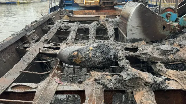 The bomb which is covered in mud laying on the bed of a cargo vessel