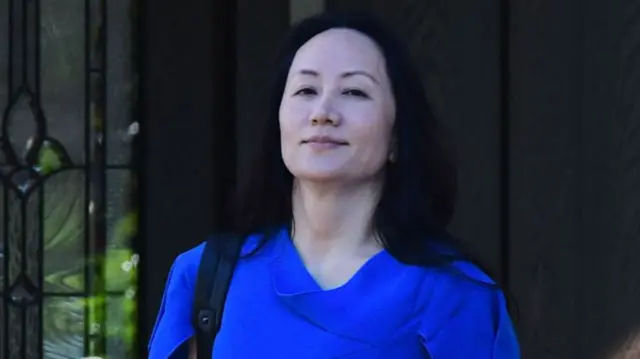 Huawei CFO Meng Wanzhou is pictured dressed in an electric blue top and a bag carried on her shoulder as she leaves her Vancouver home