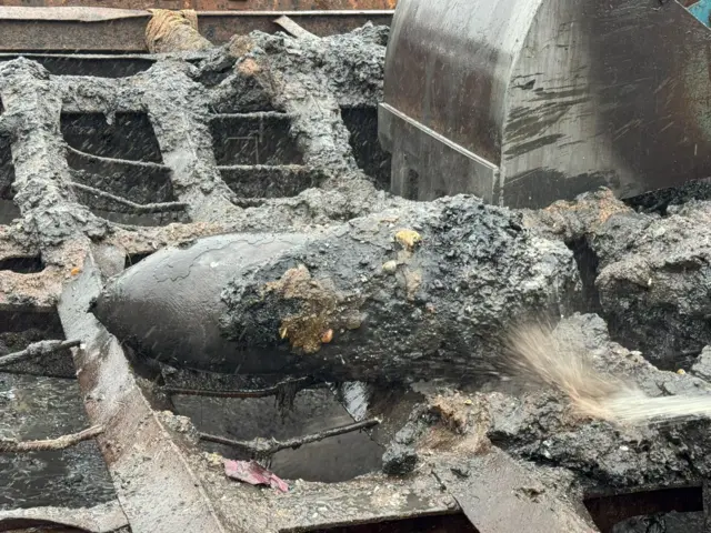 A close up picture of the bomb. A large amount of mud is on one side of it.