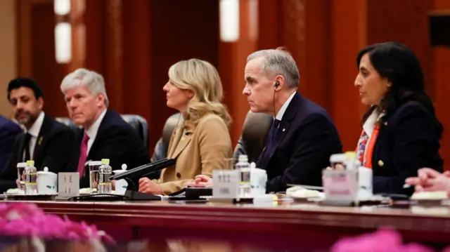 Carney sitting with his team at a long table