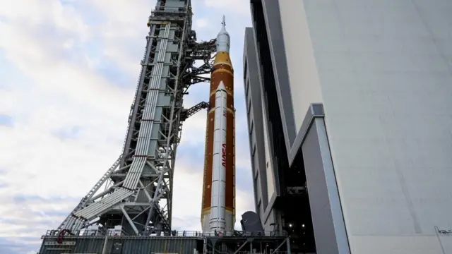 A large rocket being pulled by a large piece of machinery.