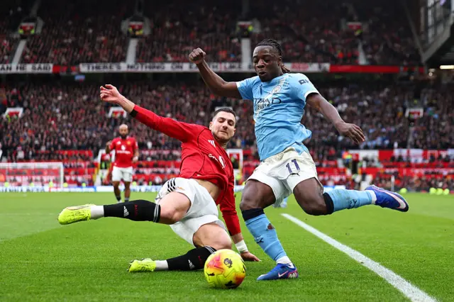Diogo Dalot of Manchester United tackles Jeremy Doku of Manchester City