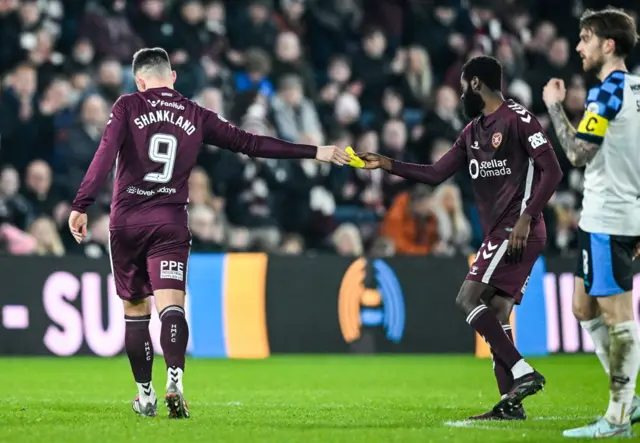 Lawrence Shankland hands over the captain's armband to Beni Baningime