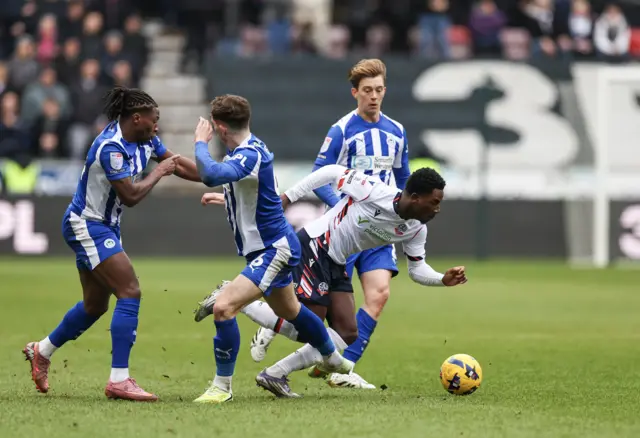Bolton Wanderers' Amario Cozier-Duberry falls to the ground after a challenge from Wigan Athletic's Jensen Weir