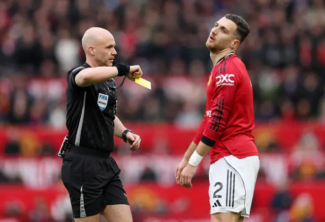 Referee Anthony Taylor shows a yellow card to Diogo Dalot
