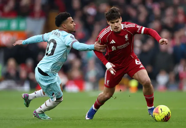 Milos Kerkez of Liverpool is challenged by Marcus Edwards
