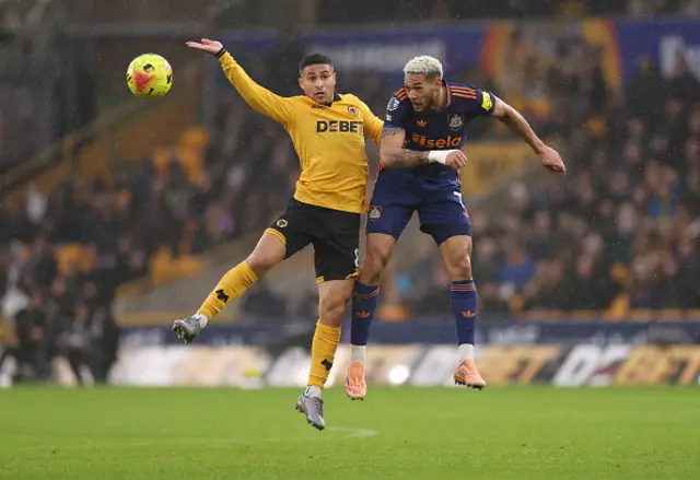 Joao Gomes of Wolverhampton Wanderers jumps for the ball with Joelinton
