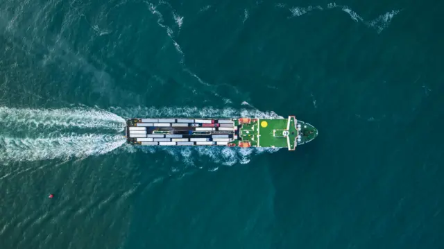 Aerial shot of a cargo ship moving across the sea