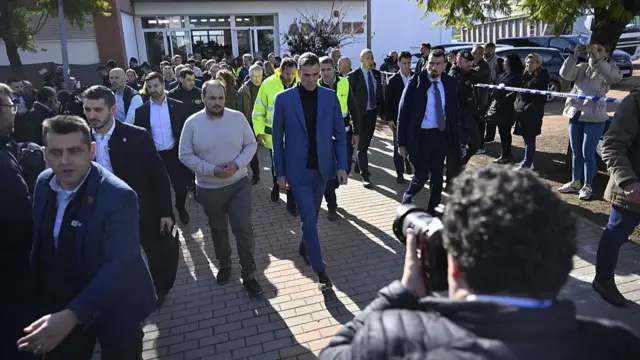 Sanchez and other Spanish officials pictured surrounded by the media outside press conference