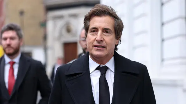 David Sherborne arriving in court this morning. He's wearing a black suit and tie and black overcoat.