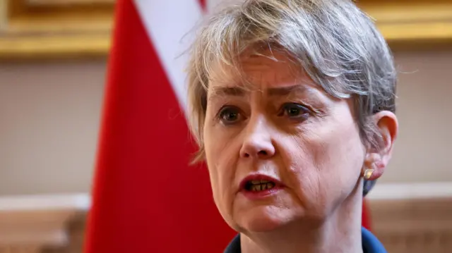 Yvette Cooper stands in front of a flag