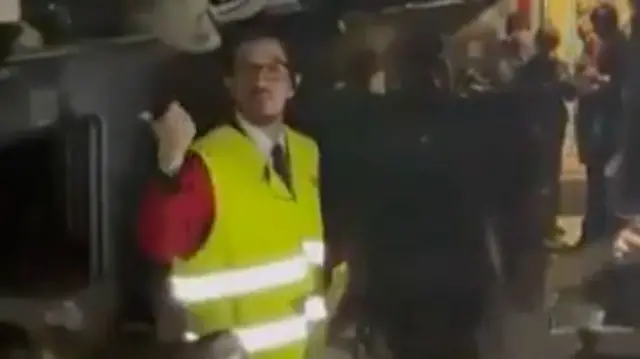 A man in a high-viz vest speaks to passengers on one of the crashed trains