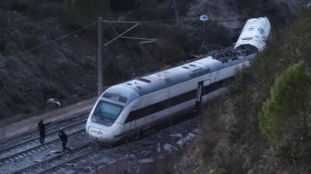 Members of the Spanish Civil Guard work next to one of the trains involved in the crash