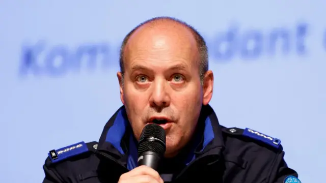 Police commander Frederic Gisler speaks at a press conference. He is wearing a uniform and is speaking into a microphone