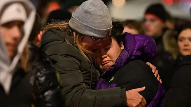 Mourners gather to leave flowers and candles at the scene after a fire broke out overnight at Le Constellation bar in Switzerland