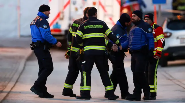 Police officers and firefighters greet each other as they arrive at the scene on 2 January