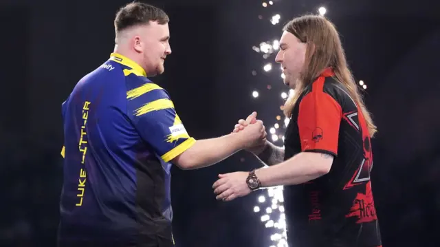 Luke Littler shakes hands with Ryan Searle