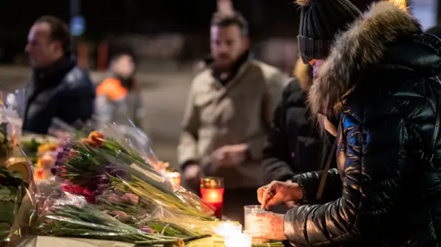 A woman lights a candle to remember the victims of the fire at the "Le Constellation" bar
