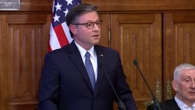 Mike Johnson in a suit and tie, speaking into a microphone.