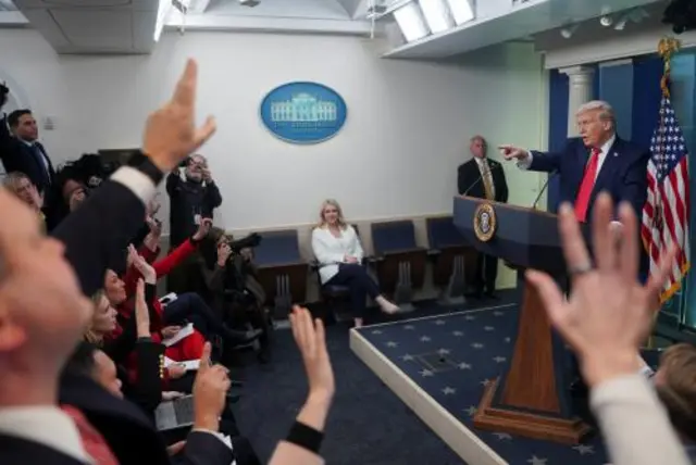 Reporters clamour to ask questions of President Donald Trump in the White House briefing room