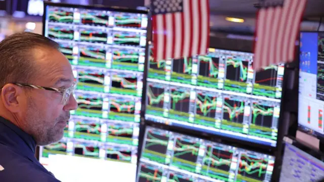 Stock trader looking at screens with graphs