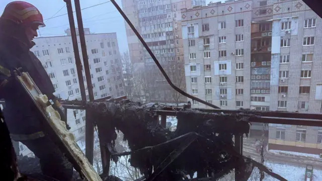 A Ukrainian firefighter looks out of a damaged building in the city of Chornomorsk following a Russian strike