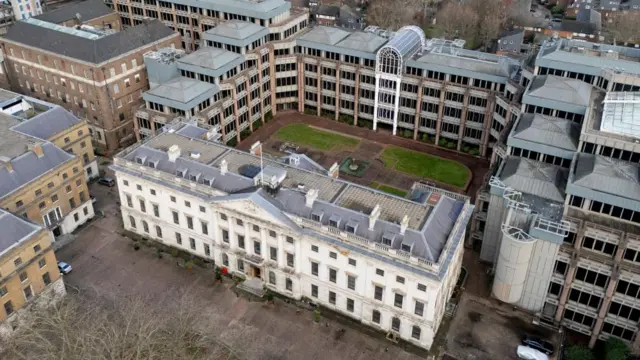 The historic main building of Royal Mint Court seen in an aerial photo which is ringed by more modern office blocks