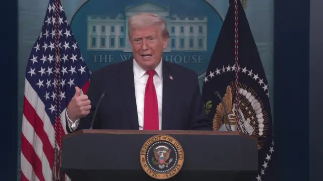 Donald Trump with his left thumb raised slightly in the air as he speaks to the media in the White House briefing room