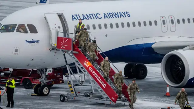 Danish soldiers climb the steps down from an Airbus airliner at Nuuk airport on Tuesday 20 January