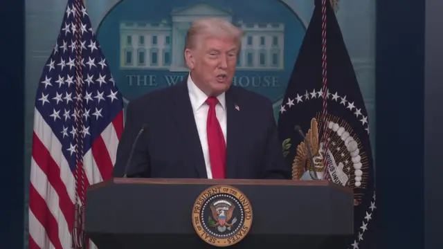 Donald Trump stands behind a podium in the White House briefing room as he speaks to the media