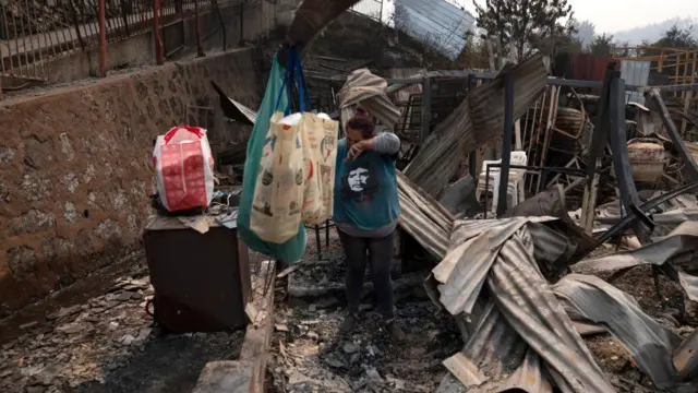 A woman cries as she picks through the wreckage of her burnt-out home in Chile's Biobio region