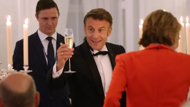 Macron holding a glass of champagne