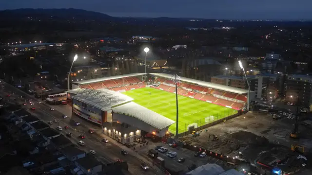 Wrexham's SToK Cae Ras stadium from above with the floodlights shining onto the pitch under the night sky before the game with Leicester