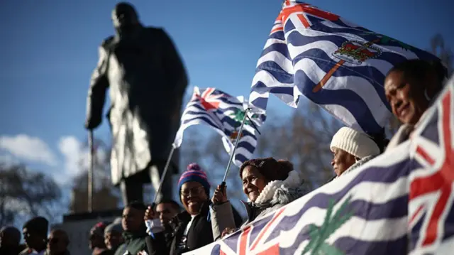 Protestors outside the houses of parliament. They're holding lots of Chagossian flags.
