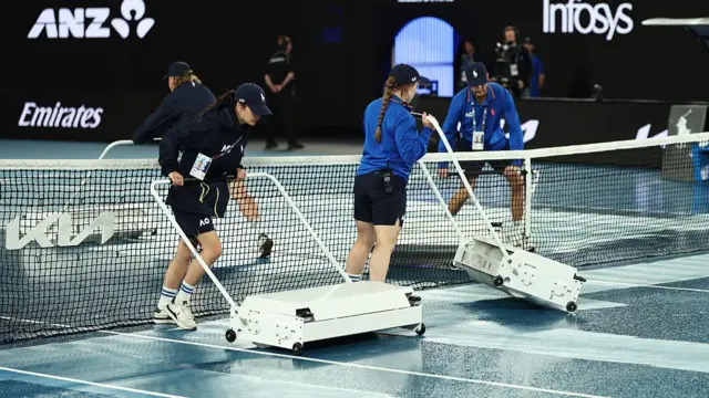 Ground staff dry the court
