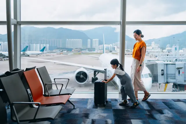 A woman walks through the airport with her child