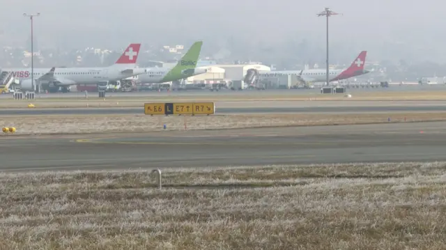 A runway with planes parked in a row