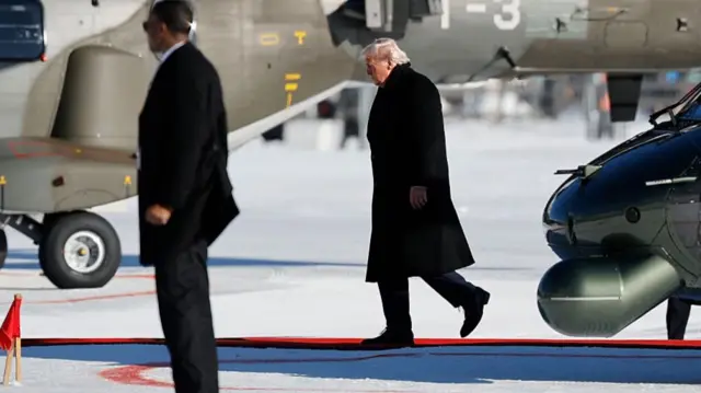 Trump is seen walking outside of helicopters on the tarmac in Davos
