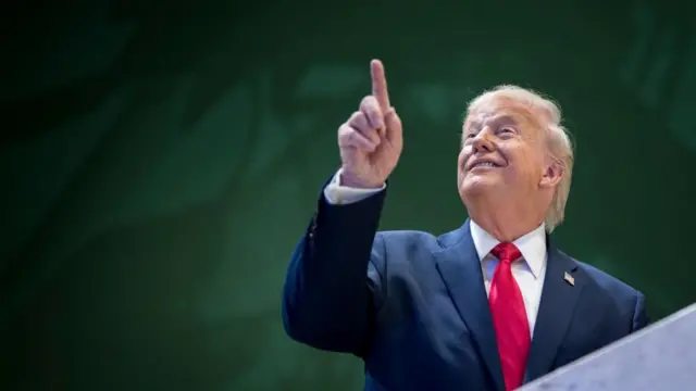 US President Donald Trump pictured in the hallway of the World Economic Forum with his left arm in the air