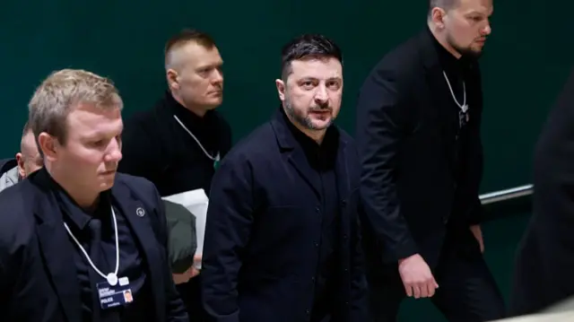 Zelensky arrives at a meeting with Trump in Davos. He's walking up the stairs here surrounded by security