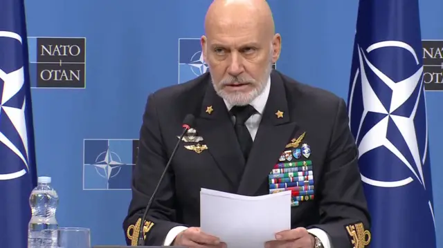 Military Committee Chair Admiral Giuseppe Cavo Dragone holds a sheet of paper as he speaks at a press conference