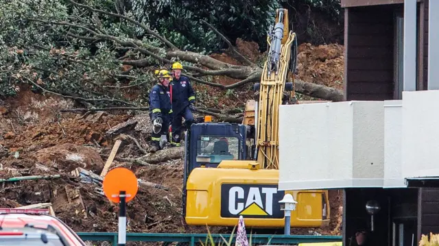 Rescuers standing on soil and debris