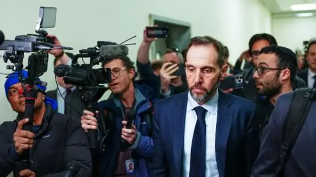 Former special counsel Jack Smith surrounded by reporters and camera crews