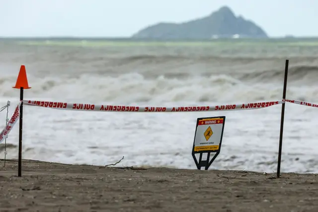 A sign advises swimmers no to go in the water, following a landslide nearby