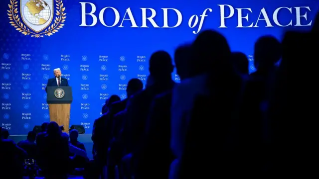 Audience members watch Donald Trump speak at the Board of Peace meeting