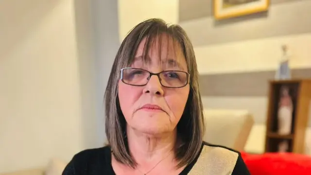 Janette sitting on a sofa looking at the camera. She looks sad