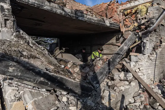 A man clears through the rubble of a home that was damaged in a strike